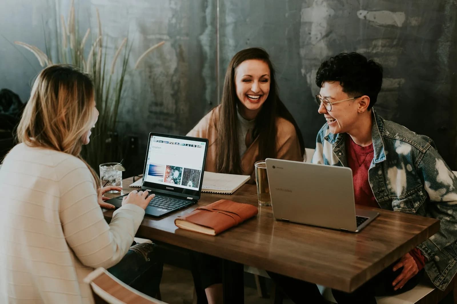 Colleagues laughing while working with laptops